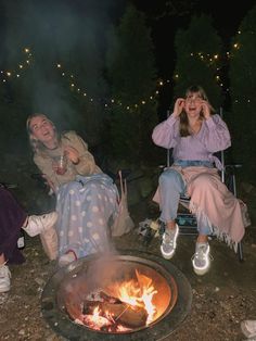 two women sitting around a campfire at night