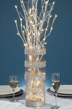 a vase filled with lights sitting on top of a table next to plates and glasses