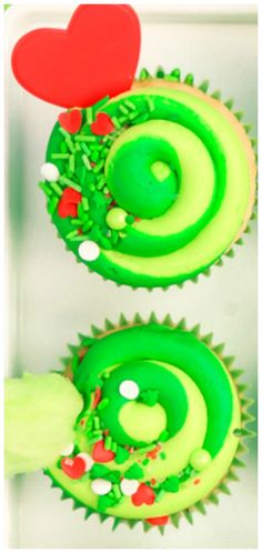 two cupcakes with green frosting and red decorations