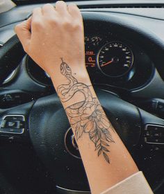 a woman's arm with a tattoo on it sitting in the driver's seat