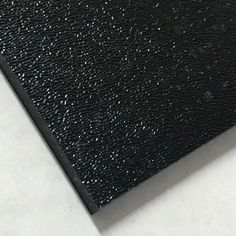 a close up view of a black leather textured surface on a white table top