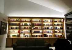 a living room filled with furniture and lots of books on the shelves in front of it