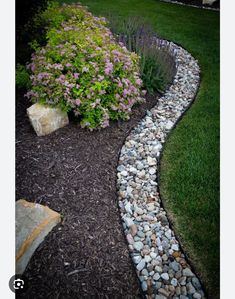 a garden with rocks and flowers in the grass next to a rock path that runs through it