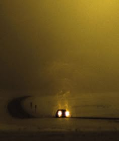 two cars driving down the road at night with fog and light coming from behind them