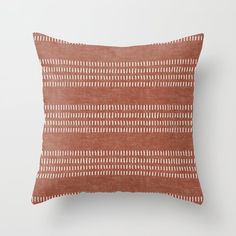 an orange and white pillow with lines on the front, sitting on a white wall