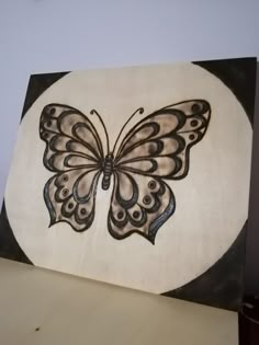 a butterfly painted on a white and black wall hanging in a room with a table