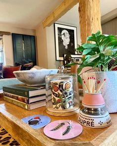 a table topped with lots of books and vases filled with plants on top of it