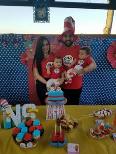 a man and woman standing next to a table with cupcakes, cake and candy