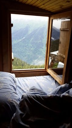 a bed sitting under a window next to a wooden frame on top of a mountain