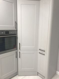 a kitchen with white cupboards and an oven in the corner next to it's door