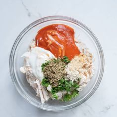 a glass bowl filled with different types of food on top of a marble countertop