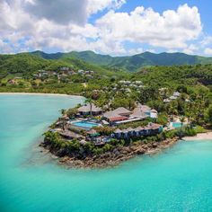 an aerial view of a tropical island in the middle of blue water and green mountains