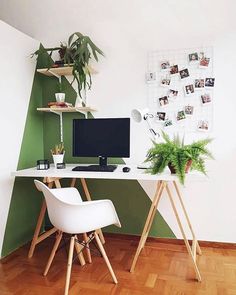 a desk with a computer on top of it next to a chair and potted plant