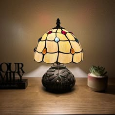 a table lamp sitting on top of a wooden table next to a potted plant