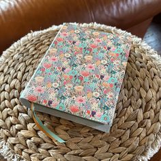 a book sitting on top of a woven basket next to a brown leather chair and pillow