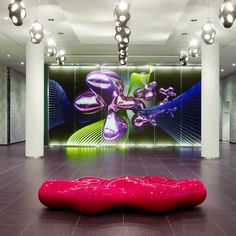 a large room with an artistic painting on the wall and red bench in front of it