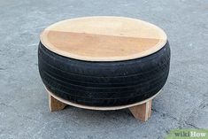 a wooden stool made out of an old tire is sitting on the concrete and looks like it has been turned into a coffee table