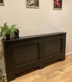 a black cabinet sitting on top of a hard wood floor next to a potted plant