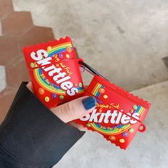 a person holding two packets of skittles