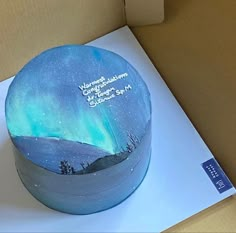 there is a cake in the box with an aurora bore on it and stars above