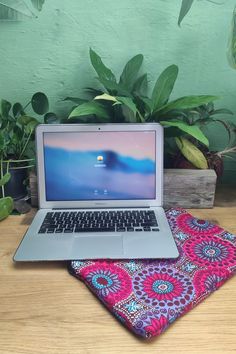 an open laptop computer sitting on top of a table next to a potted plant