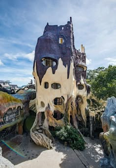 an unusual house built into the side of a tree stump in front of a blue sky