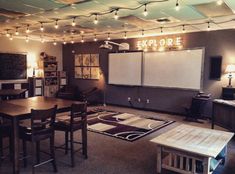 a room with tables, chairs and whiteboards on the wall