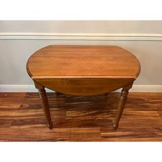 a wooden table sitting on top of a hard wood floor next to a white wall