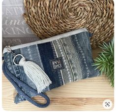 a purse with a tassel on it sitting next to a plant and straw hat