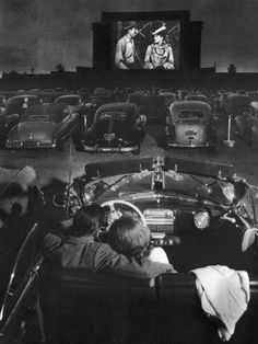 an old photo of people in cars watching a movie on a large screen at the movieshow