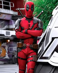 a man dressed as deadpool standing in front of a car with his arms crossed