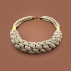 a white and yellow rope necklace on a brown background