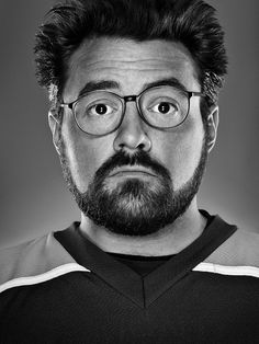 a man with glasses and a beard is looking at the camera while wearing a jersey