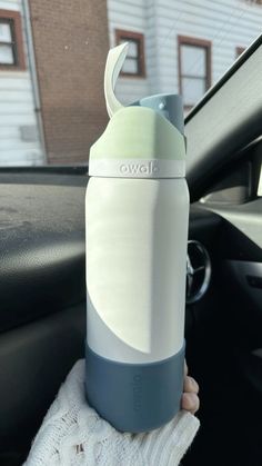 a person holding up a water bottle in their car