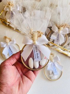 a hand holding a bag filled with white eggs in front of two gold hoop holders