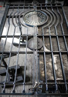 an old clock is sitting on top of a metal grate in the middle of a room