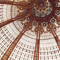 an ornate ceiling in a building with glass and metal designs on the ceiling, looking up into the sky