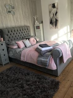 a bedroom with a bed, chair and rugs on the wooden floored floor