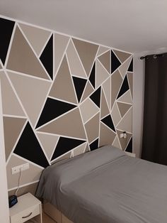 a bed sitting in a bedroom next to a wall with geometric designs on the walls