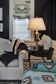 a living room filled with furniture and a lamp on top of a coffee table in front of a window