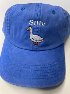 Looking for a fun and quirky accessory to add to your everyday look? Look no further than the None Silly Goose Dad Hat! Crafted from high-quality materials by trusted maker Port Authority, this washed blue hat is the perfect way to add a touch of humor to your outfit. The hat's playful design features a silly goose graphic front and center, adding an element of lighthearted fun that's sure to turn heads. With its comfortable fit and adjustable strap, this Dad Hat is perfect for any casual occasi Cheap Fun Blue Hats, Denim Blue Summer Hat For Everyday, Denim Blue Summer Hat, Denim Blue Baseball Cap For Spring, Trendy Adjustable Soft-washed Hat, Trendy Washed Hats With Curved Bill, Trendy Washed Curved Bill Hats, Summer Washed Hats, One Size Fits Most, Summer Washed Hat, One Size Fits Most