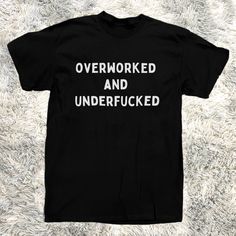 Introducing The T-Shirt That Speaks Your Truth Louder Than Your Boss Yells At You The "Overworked And Underfucked" Men's Tee! Crafted From 100% Pure Cotton, This Black Beauty Is Perfect For Those Who Need A Laugh As Much As They Need A Vacation. Wear It To The Office, The Bar, Or Your Next Therapy Session Wherever The Truth Needs To Be Told. Warning: This Shirt May Cause Spontaneous High-Fives And Knowing Nods From Fellow Sufferers. Funny Saying For Shirts, Sarcastic Shirts For Men, Black Slogan Shirt In Grunge Style, Black Tops With Funny Text For Streetwear, Black Relaxed Fit T-shirt With Funny Text, Funny Black Shirt With Letter Print, Funny Black Slogan Shirt, Black Funny Slogan Shirt, Funny Black T-shirt With Logo Print