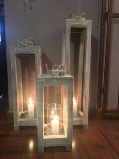 two wooden lanterns with candles in them sitting on a wood floor next to a mirror