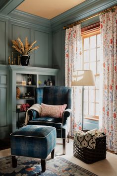 a blue chair and ottoman in a room with curtains on the window sill, potted plant next to it