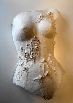 a white plaster sculpture with flowers on it's back and the top part of its body