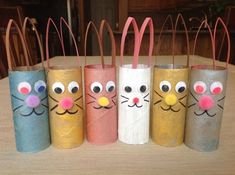 four toilet paper rolls with faces painted on them sitting on top of a wooden table