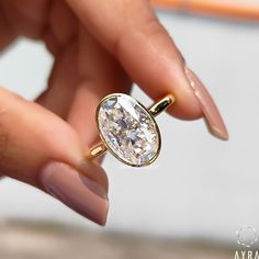 a woman's hand holding an engagement ring with a diamond in the center and gold band