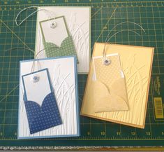 three cards are sitting next to each other on a cutting board with scissors and thread