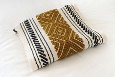 a white and brown pillow on top of a bed next to a black and white blanket