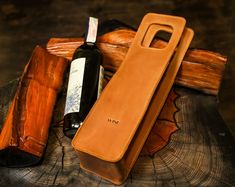 a bottle of wine sitting on top of a wooden table next to a leather case